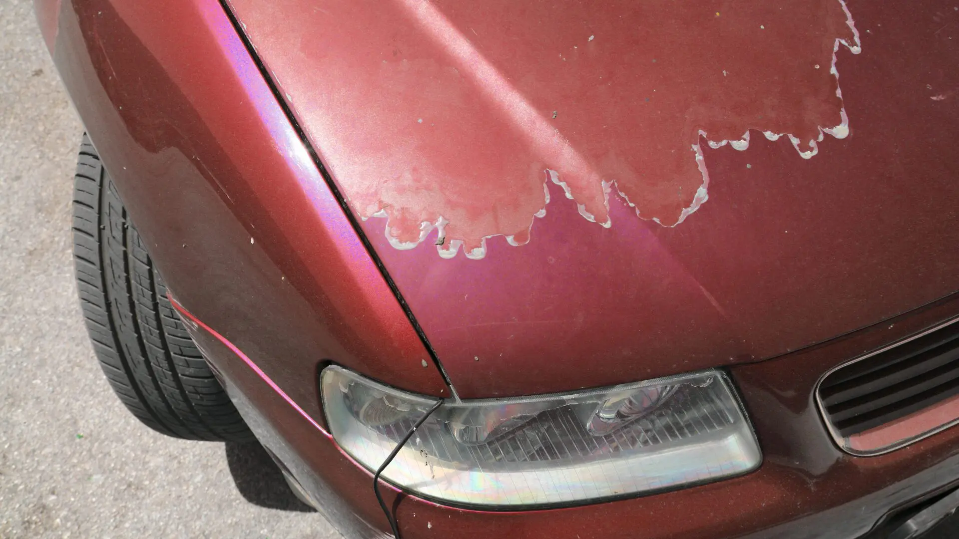 Close-up of car paint with visible cracks and peeling, illustrating damage caused by exposure to extreme temperatures.