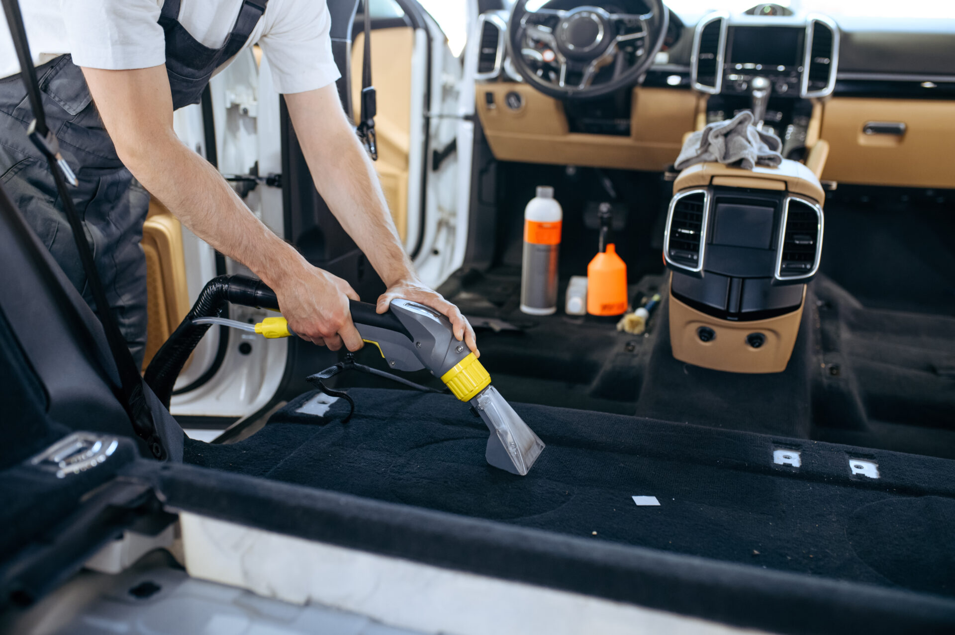 worker cleans car interior with vacuum cleaner