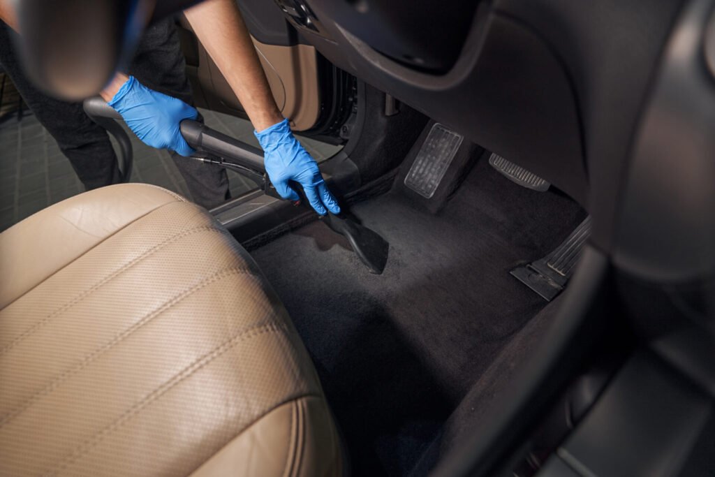 worker cleans car interior with vacuum cleaner