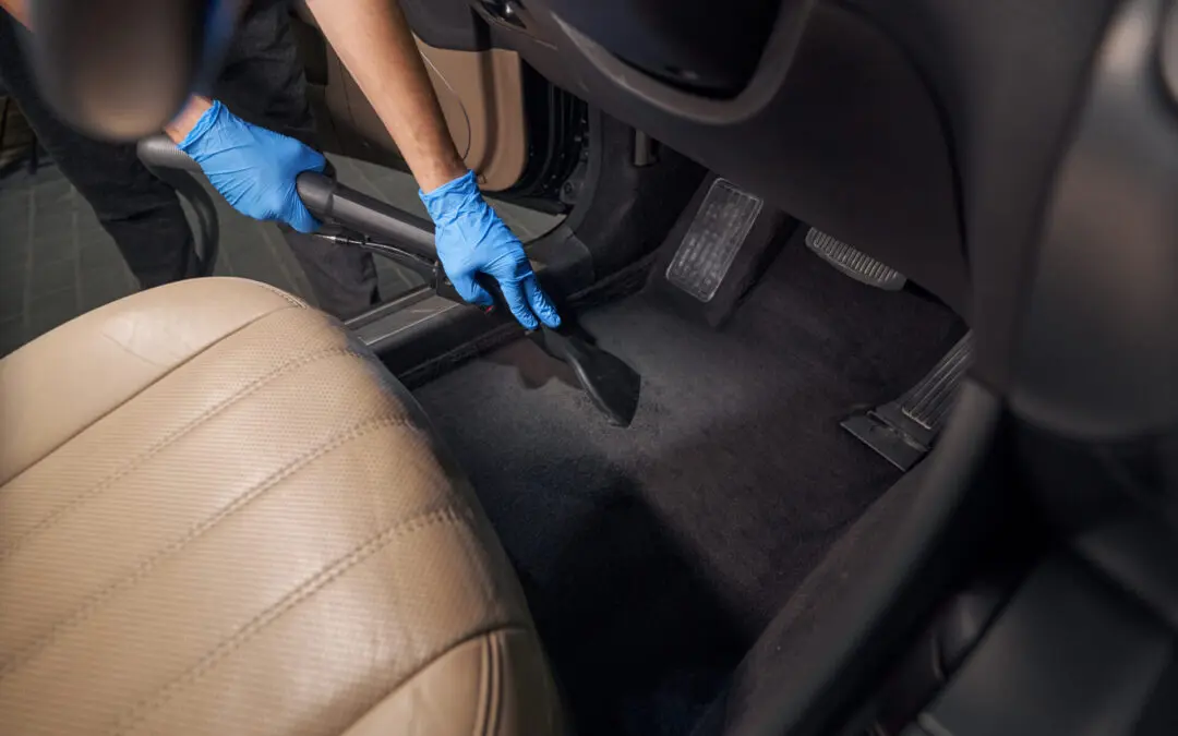 worker cleans car interior with vacuum cleaner