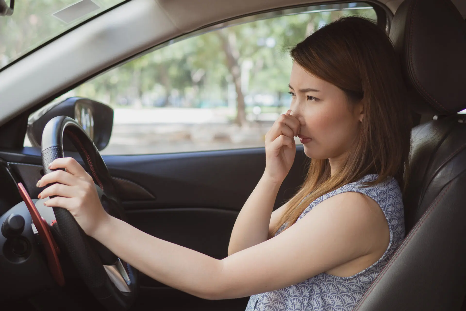 young woman in car holding nose